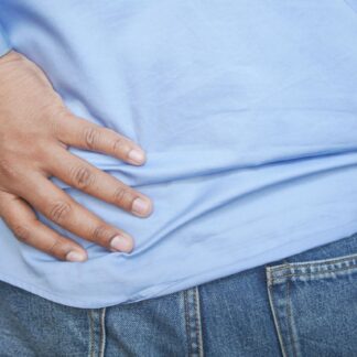 Persona con la mano apoyada en la zona lumbar por dolor de espalda